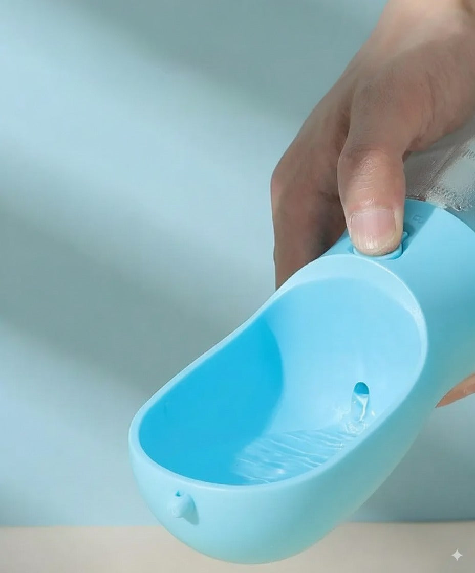 Close-up of a hand pressing the lock button on a blue portable dog water bottle to dispense water into the ergonomic cup, showing the one-hand operation.