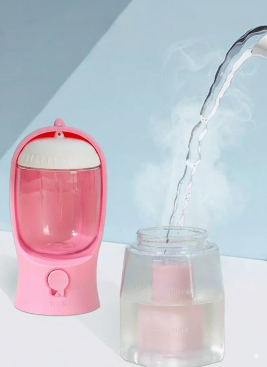 A pink portable dog water bottle being easily refilled in seconds by pouring fresh water into its wide-mouth opening.